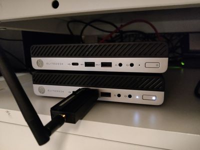 Two stacked mini PCs beside a small Wi-Fi-equipped thin client